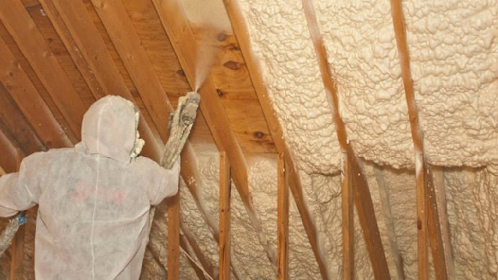 Technician applying spray foam insulation in attic space