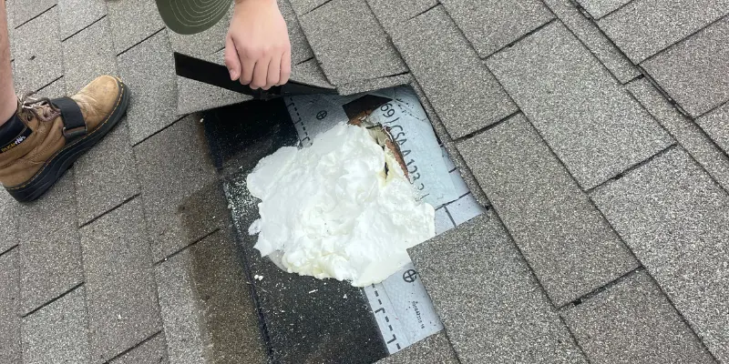 Technician applying spray foam insulation on roof vent area